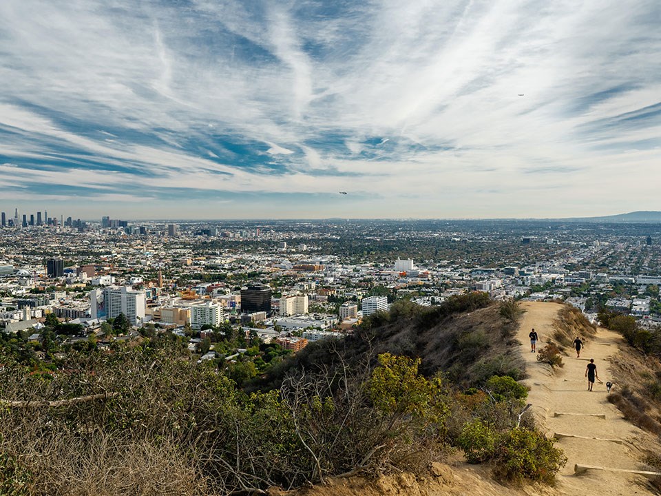 Sweeping views over Los Angeles city from a mountain hike trail with people walking