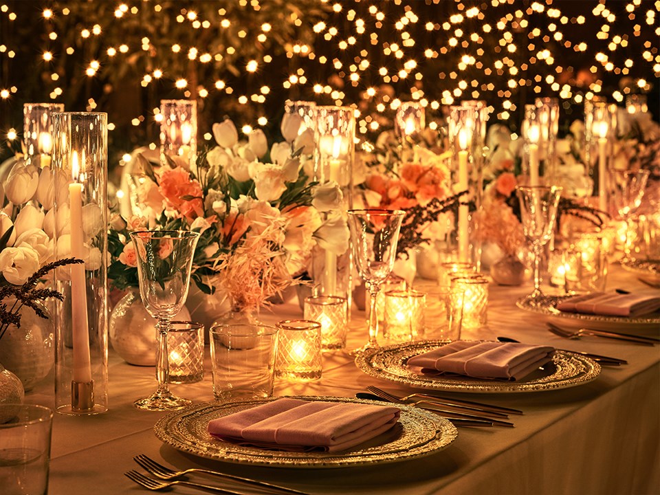 Candles and plates arranged on a table with a backdrop of fairylights in the Garden Terrace