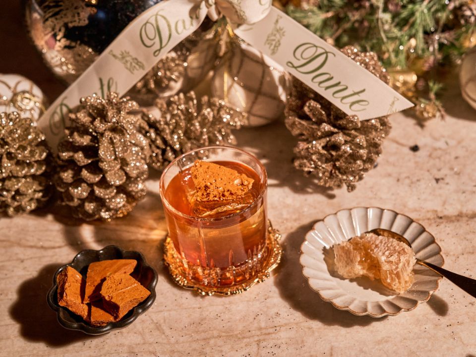 a festive cocktail displayed with pine cones and a sparkly wreath