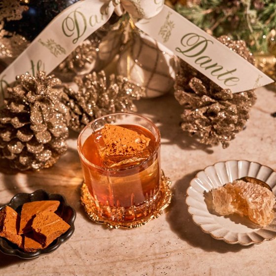 a festive cocktail displayed with pine cones and a sparkly wreath