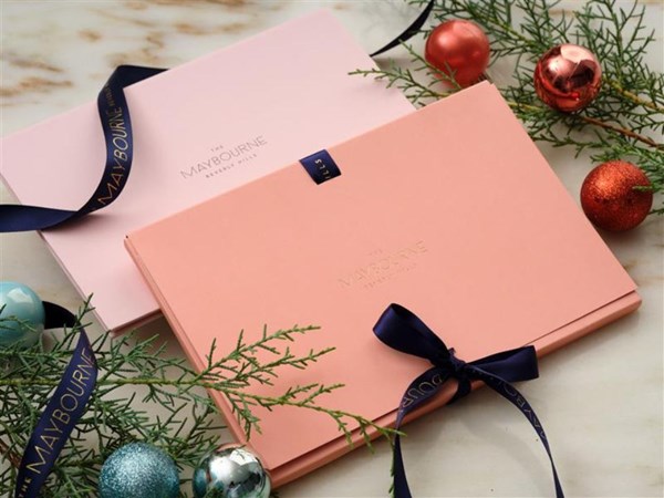 a festive gift voucher package surrounded by ornaments and pine cones