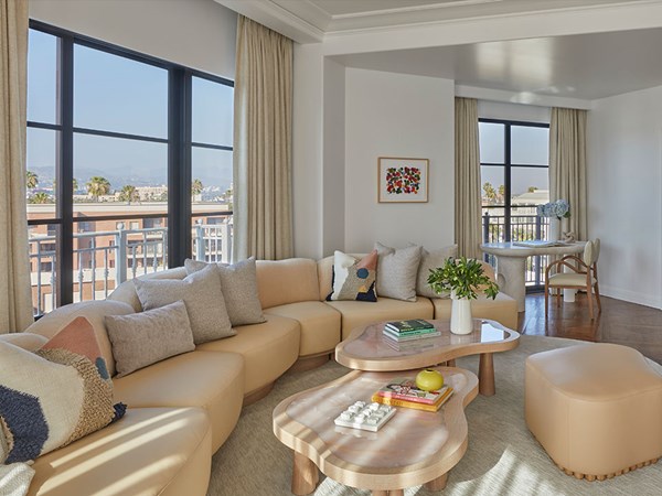 Large beige L-shaped sofa with chic cushions in the living room of a large suite filled with sunlight