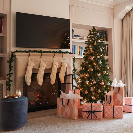 Christmas tree with wrapped gifts and stockings hung on a fireplace