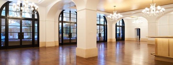 Empty event space with chandeliers and  french doors letting in natural light