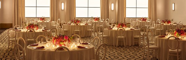 Set up of white tables and chairs, with candles and floral decorations in the evening in the ballroom