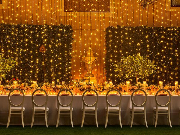 Hanging fairy lights as a backdrop to a long table set up for an event in the Garden Terrace