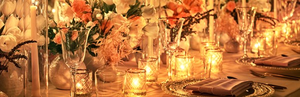 Dinner settings and candles laid out on a table for an evening event