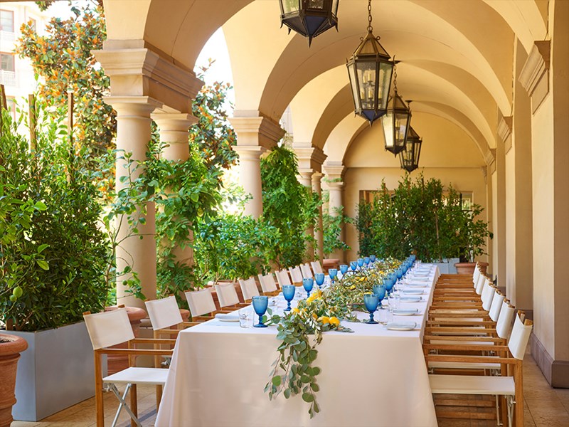 Long table set out for a private day dining event with lemons and greenery on the middle