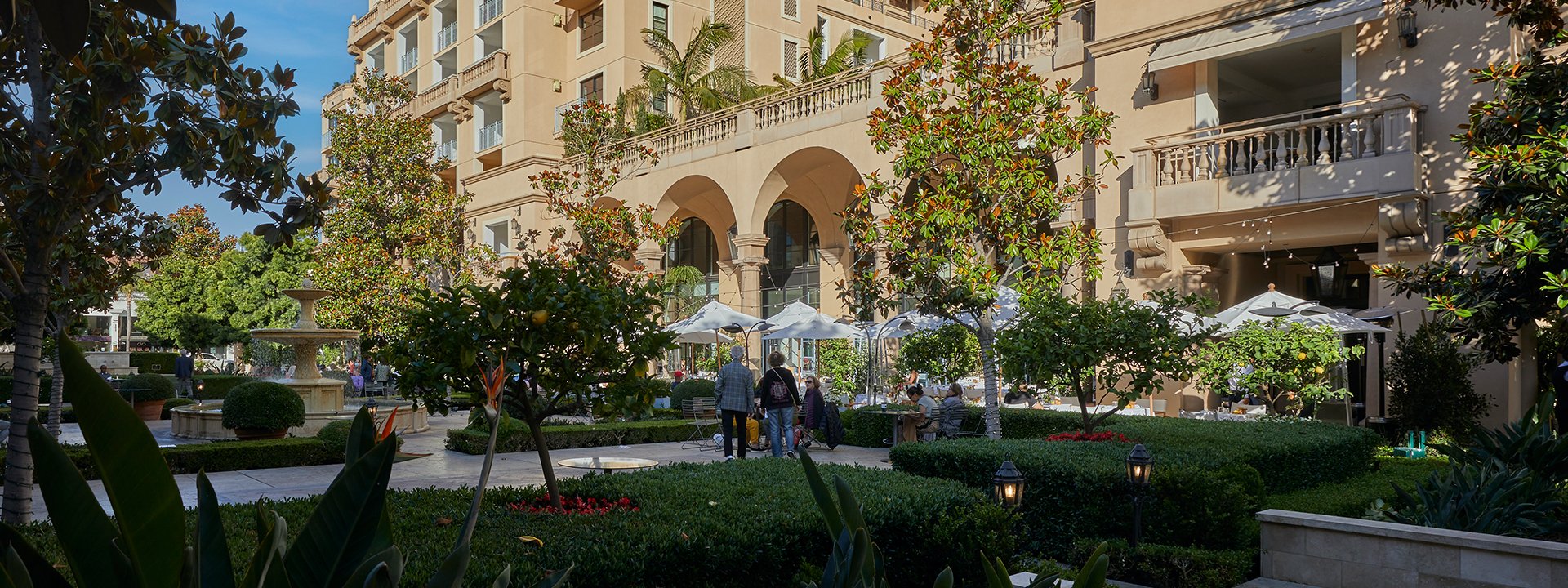 People walking through the green lawns and plants of Beverly Canon Gardens