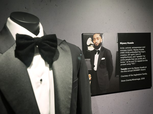 Close up of a tuxedo on a mannequin with a wall plaque in a museum exhibit