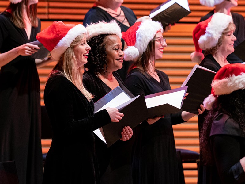 Women in santa hats singing carols