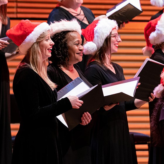 Women singing in Santa hats at a carol concert