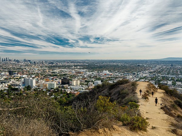 People hiking on canyon trail overlooking Los Angeles city skyline