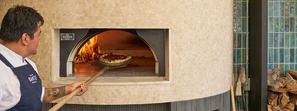 Chef placing stonebaked pizza in pizza oven