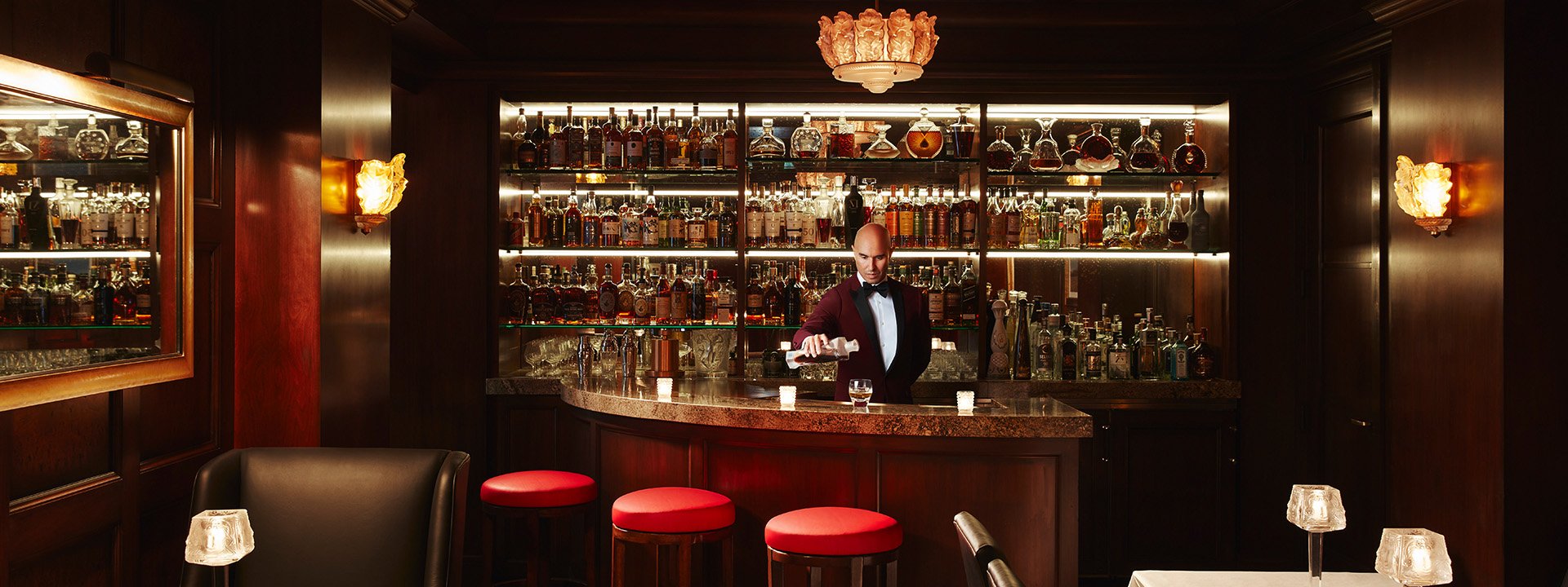 Barman mixing a cocktail in dark wooden Cigar and Whiskey Bar