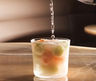 Cocktail with colorful ice being pourd