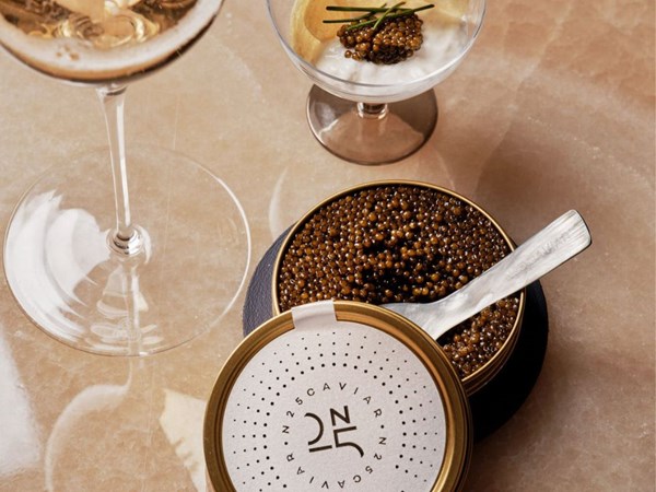 an open tin of black caviar with a champagne flute next to it