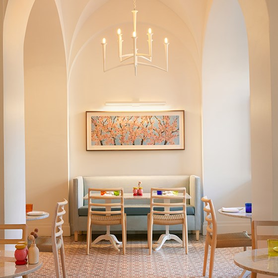 A light blue booth and table at The Maybourne Café. There is a photo of a pink blossomed tree above the booth.