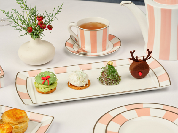 a festive afternoon tea set-up with holiday inspired pastries as a snowflake, reindeer, christmas tree, and festive wreath