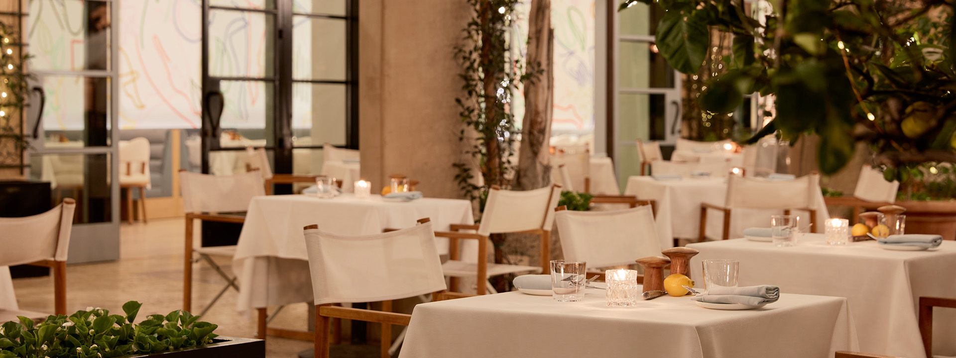 The outside dining area of The Terrace restaurant at night. Tables are set with candles in the middle.