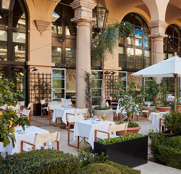 A landscaped restaurant patio, lush and well-designed, provides a delightful outdoor dining experience with greenery.