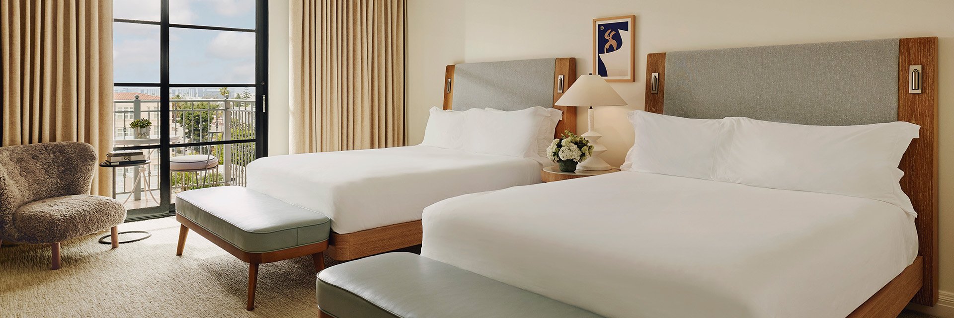 Neat bedroom, two beds, table with a handy lamp in between for convenience, and a comfy sitting chair.