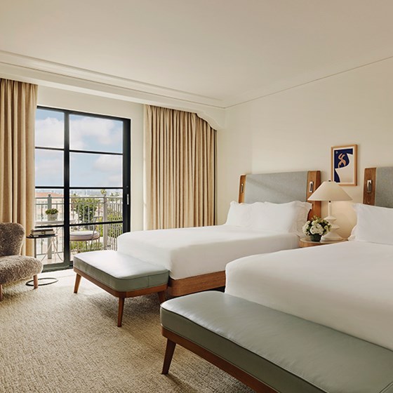 Neat bedroom, two beds, table with a handy lamp in between for convenience, and a comfy sitting chair.