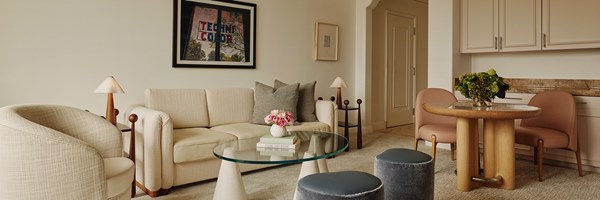 Neat living space, comfy couch, glass coffee table, adorned with an overhead portrait that reads 