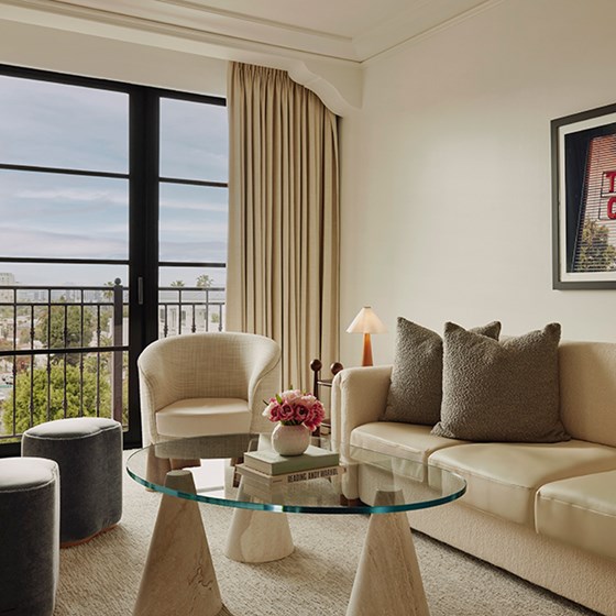 A seating area in the Library Suite. The room has a sleek theme and features a plush cream sofa and chic fabric stools.