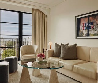 A seating area in the Library Suite. The room has a sleek theme and features a plush cream sofa and chic fabric stools.