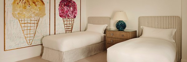 Two twin beds in a room with two large modern paintings of ice cream cones.