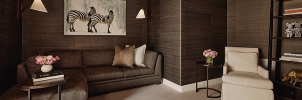 An L-shaped couch in a black room with a zebra painting. There's a sitting chair by a shelf with mouse figures.