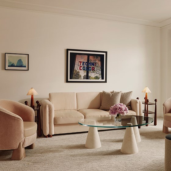 Neat living space, comfy couch, glass coffee table, adorned with an overhead portrait that reads