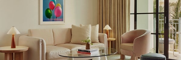 An ivory couch with two side tables. A coffee table with a plant sitting on two books. Sliding glass doors to a terrace.