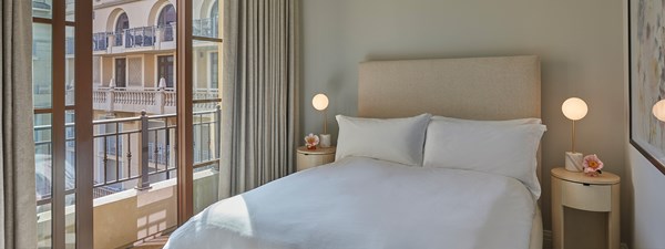 Guest bedroom with king size bed and white bedding in cream decor in The Residence