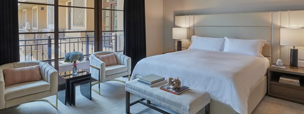 Master bedroom with king size bed, white linen and two plush velvet chairs in The Residence