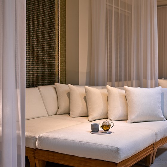 On the couch, an elegant kettle, cup, and tray beckon relaxation and comfort.