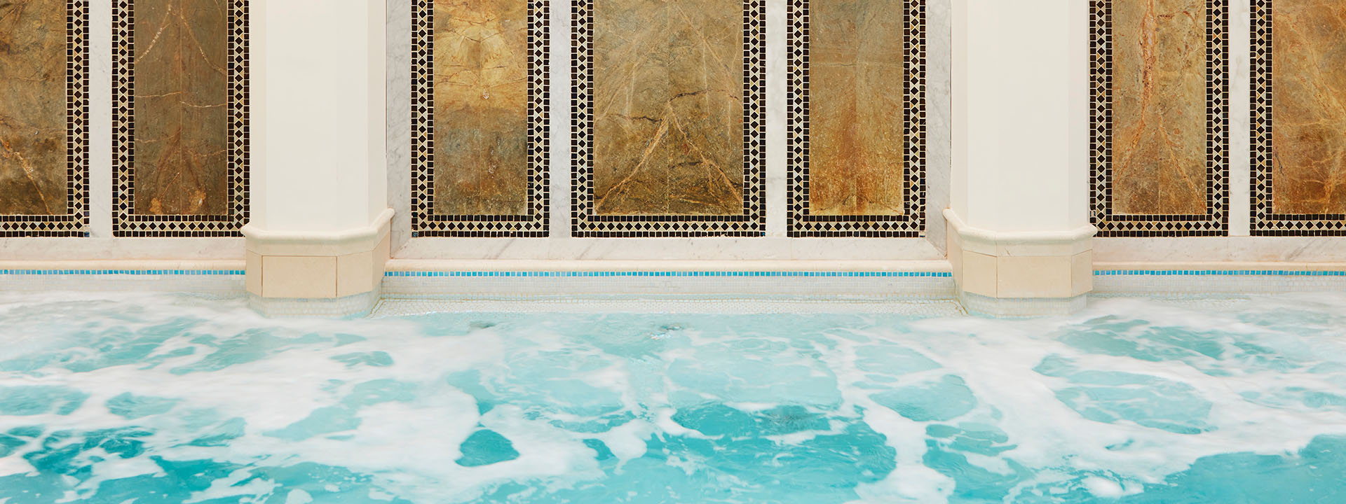 A large mineral pool at a spa with mosaic walls.