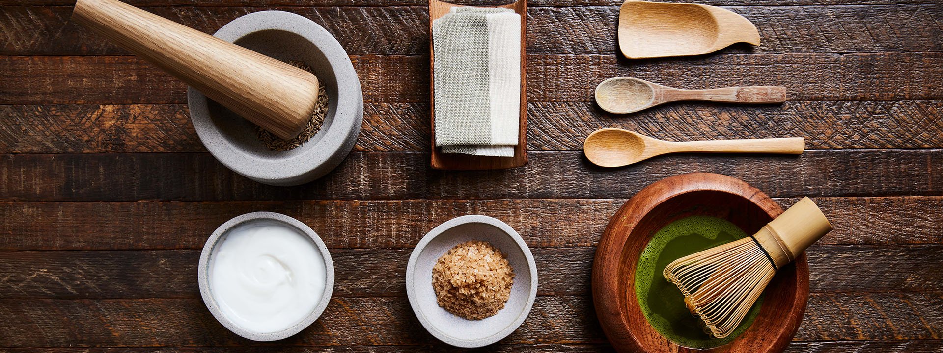 Bowls and plates on a wooden table filled with healing salts, spices, and creams used for spa treatments
