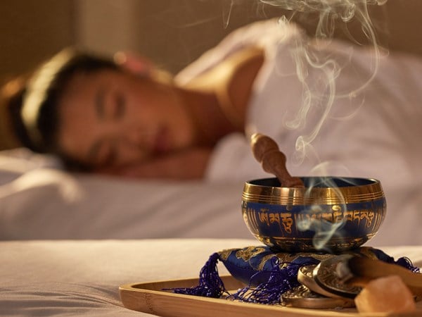 Woman in a spa robe laying down with palo santo burning