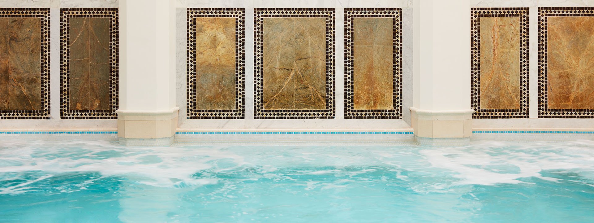 An elegant poolside wall design enhances the surroundings with its beautiful decorative touch.