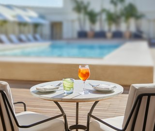 Poolside table and chairs with a chilled cocktail