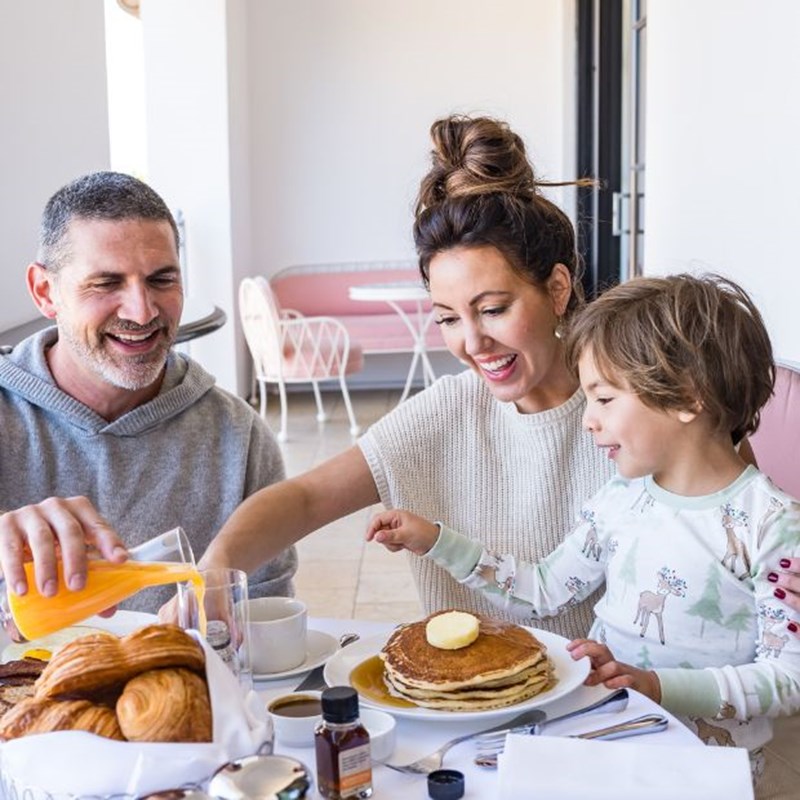 mother and family having in-room dining breakfast on the patio with their kid