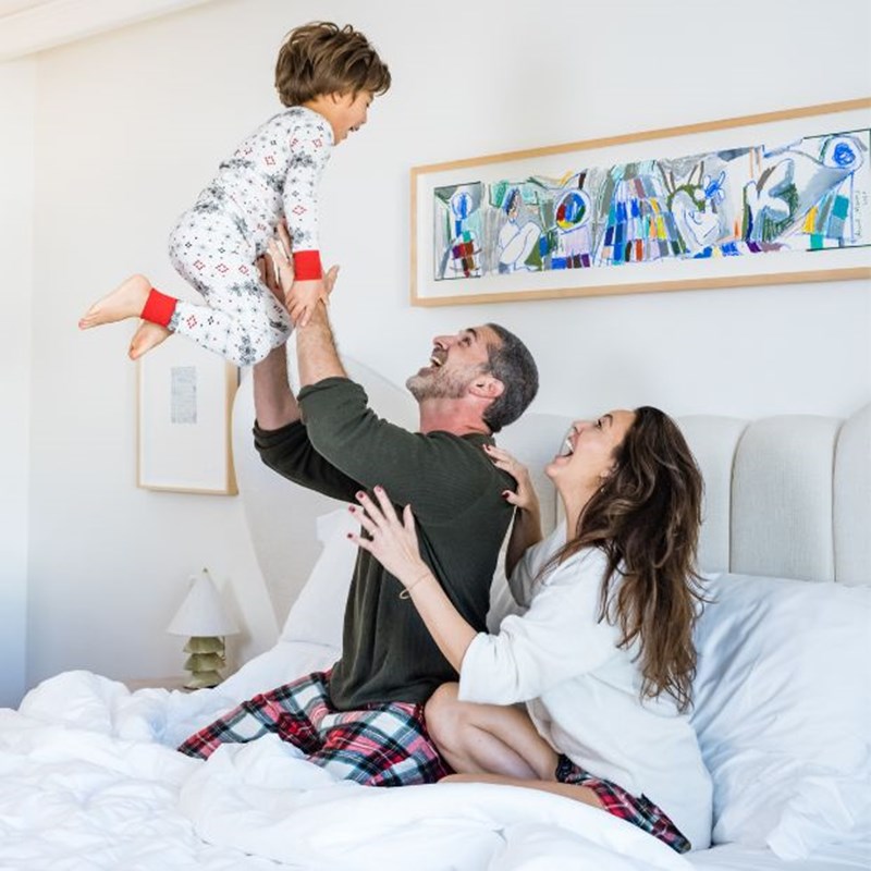 parents tossing their kid in bed in a playful manner
