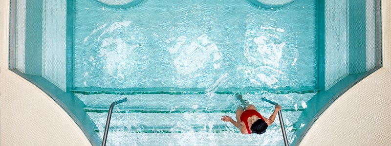 A woman stepping in the pool at The Maybourne Beverly Hills spa