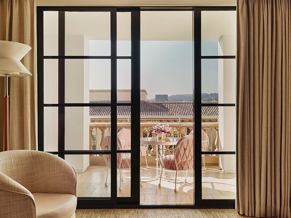 Balcony view from a suite with a small table and chairs overlooking terracotta rooftops.